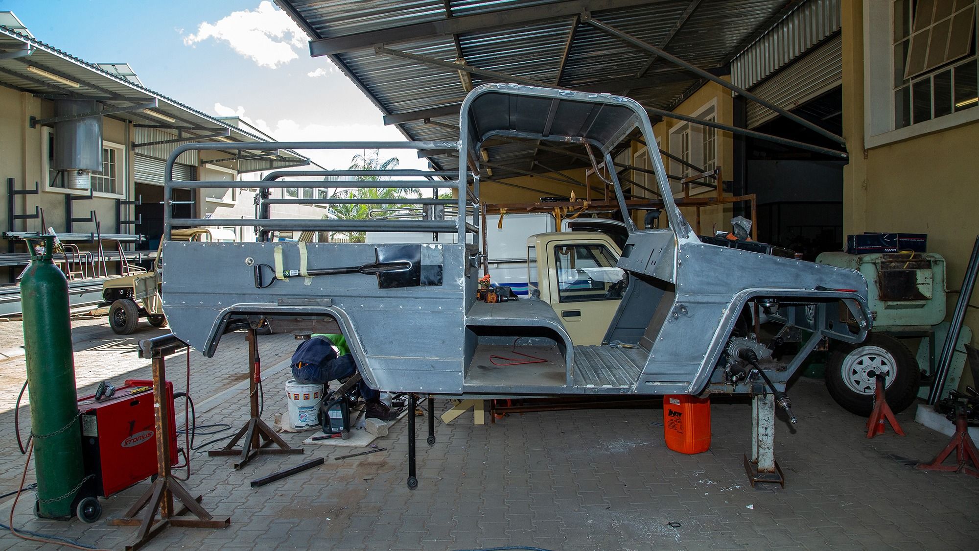 Werkstatt von DIS Engineering: Karosserie eines Elektrofahrzeugs im Aufbau, ein Mitarbeiter arbeitet am Fahrwerk.